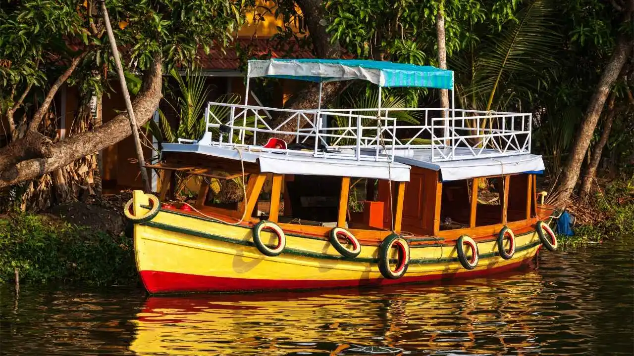 Shikara boat ride through the narrow canals of Alleppey backwaters surrounded by coconut trees in Kerala