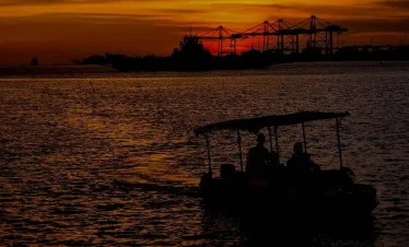 a group of people in a boat on water with a sunset in the background